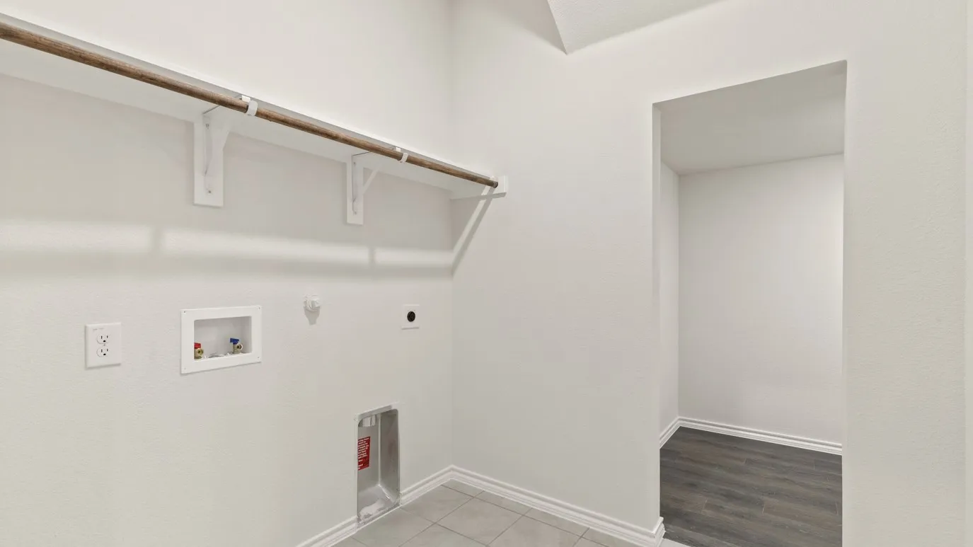 Laundry area featuring a hanging rod, wall-mounted shelving, and tile flooring