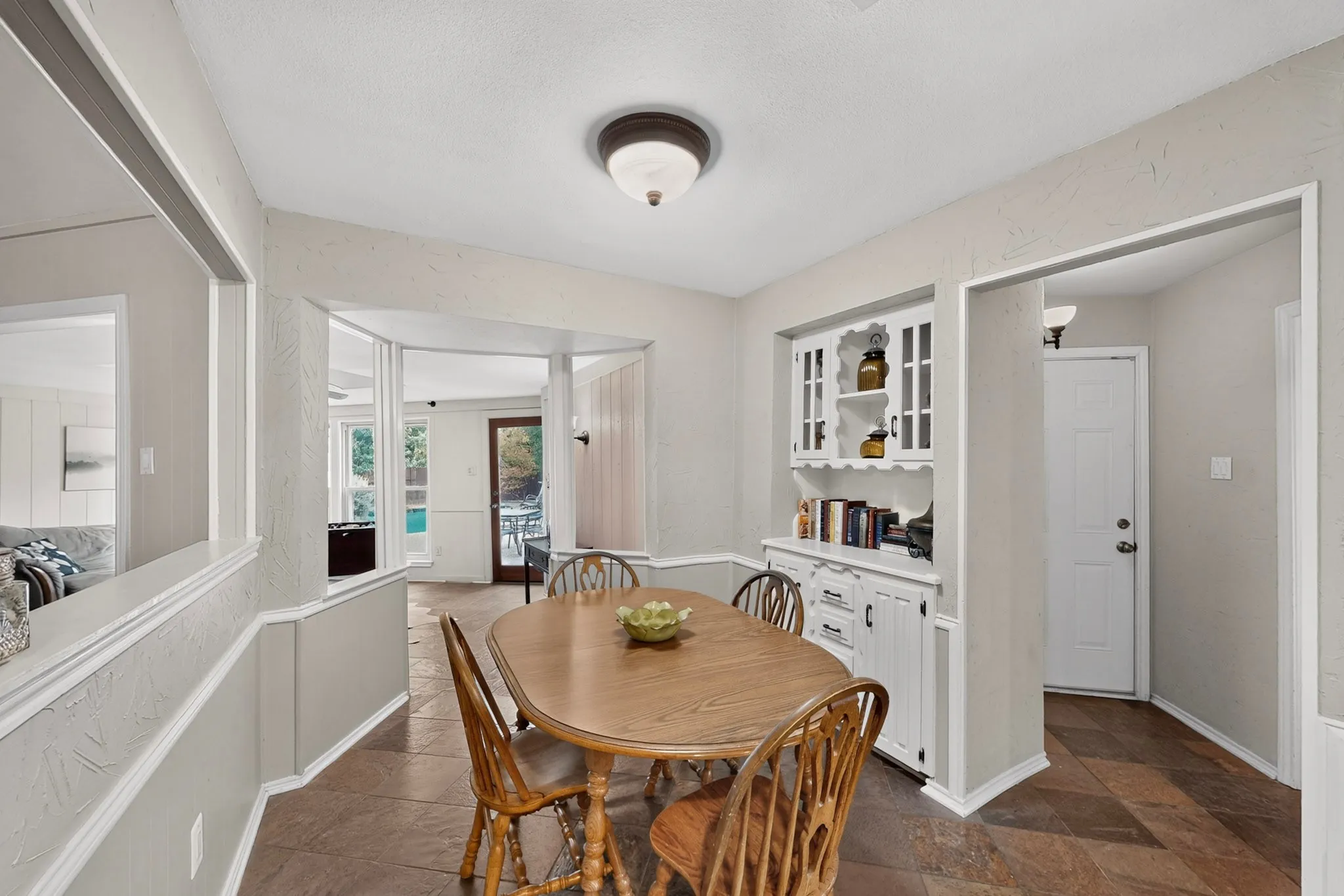 Dining area featuring tile flooring, a built-in hutch with glass-front cabinetry, and a ceiling-mounted light fixture
