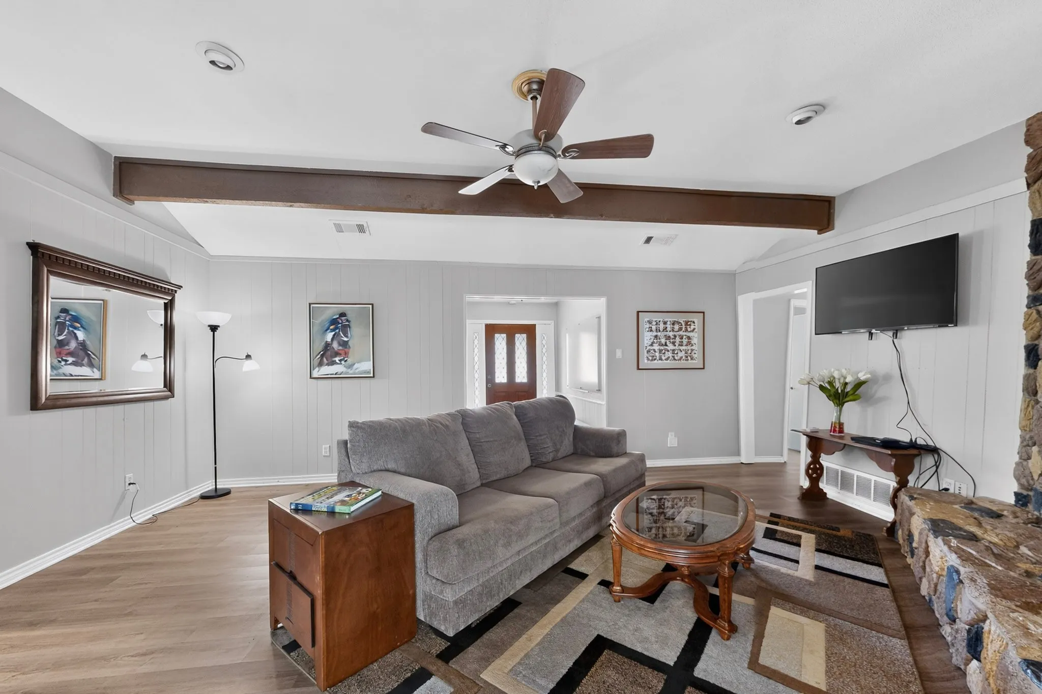 Spacious living area featuring wood-finish flooring, a ceiling fan, recessed lighting, and a stone-clad fireplace