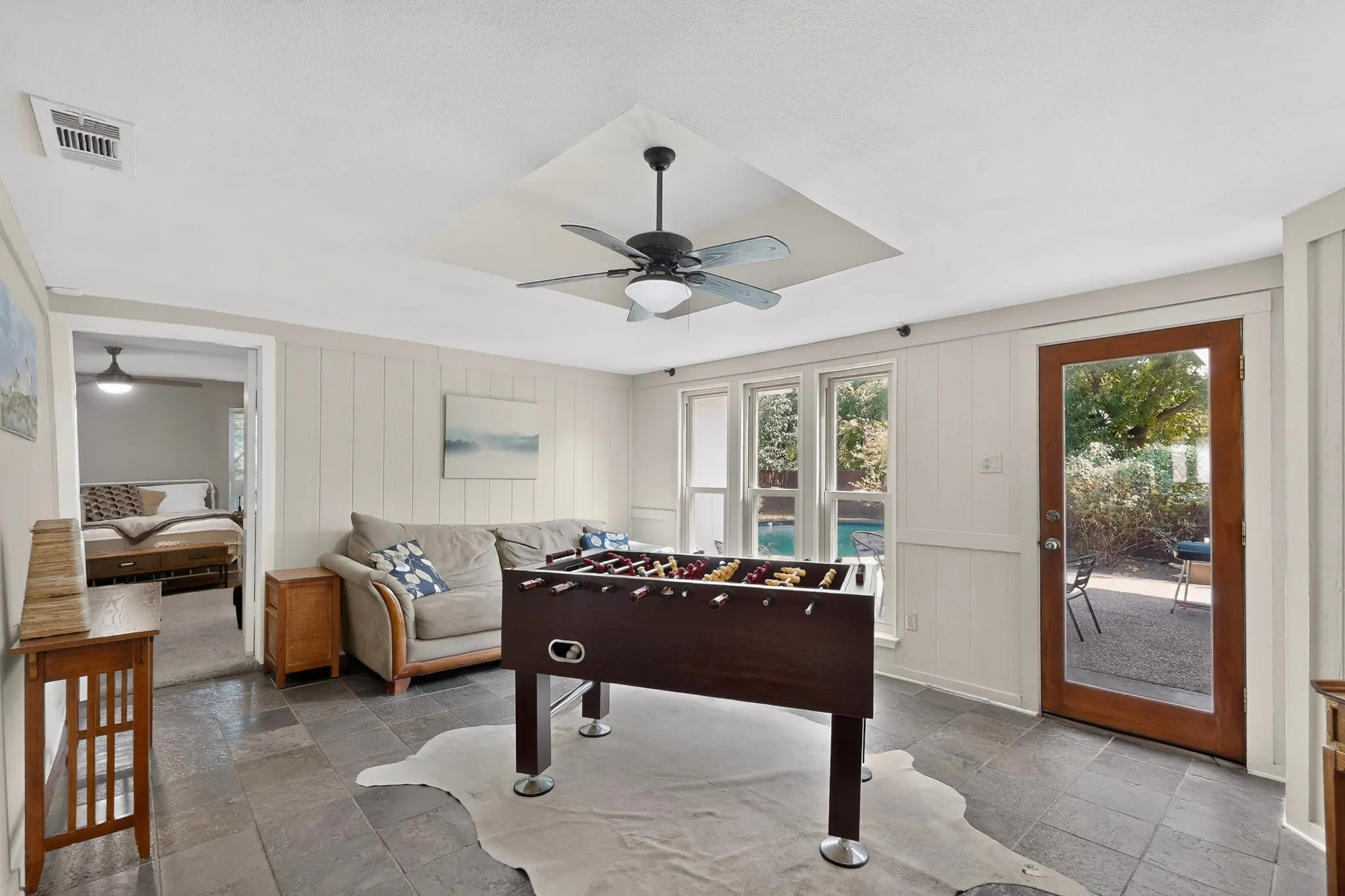 Slate tile flooring, recessed ceiling fan with lighting, wood-paneled walls, and a glass-paneled exterior door