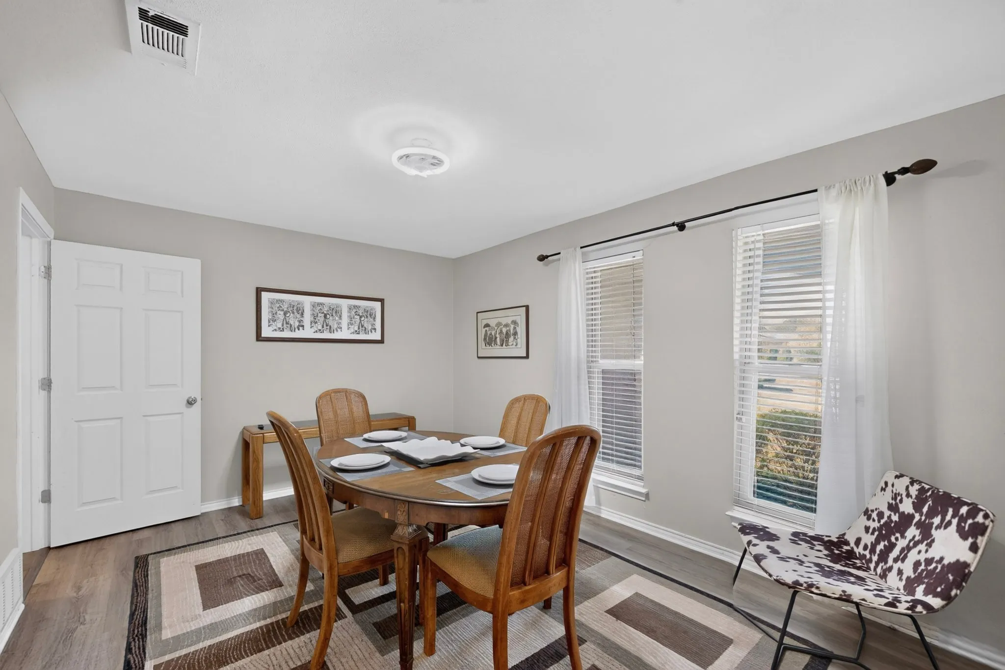 Wood-finish flooring, light grey wall paint, and multiple windows with white blinds