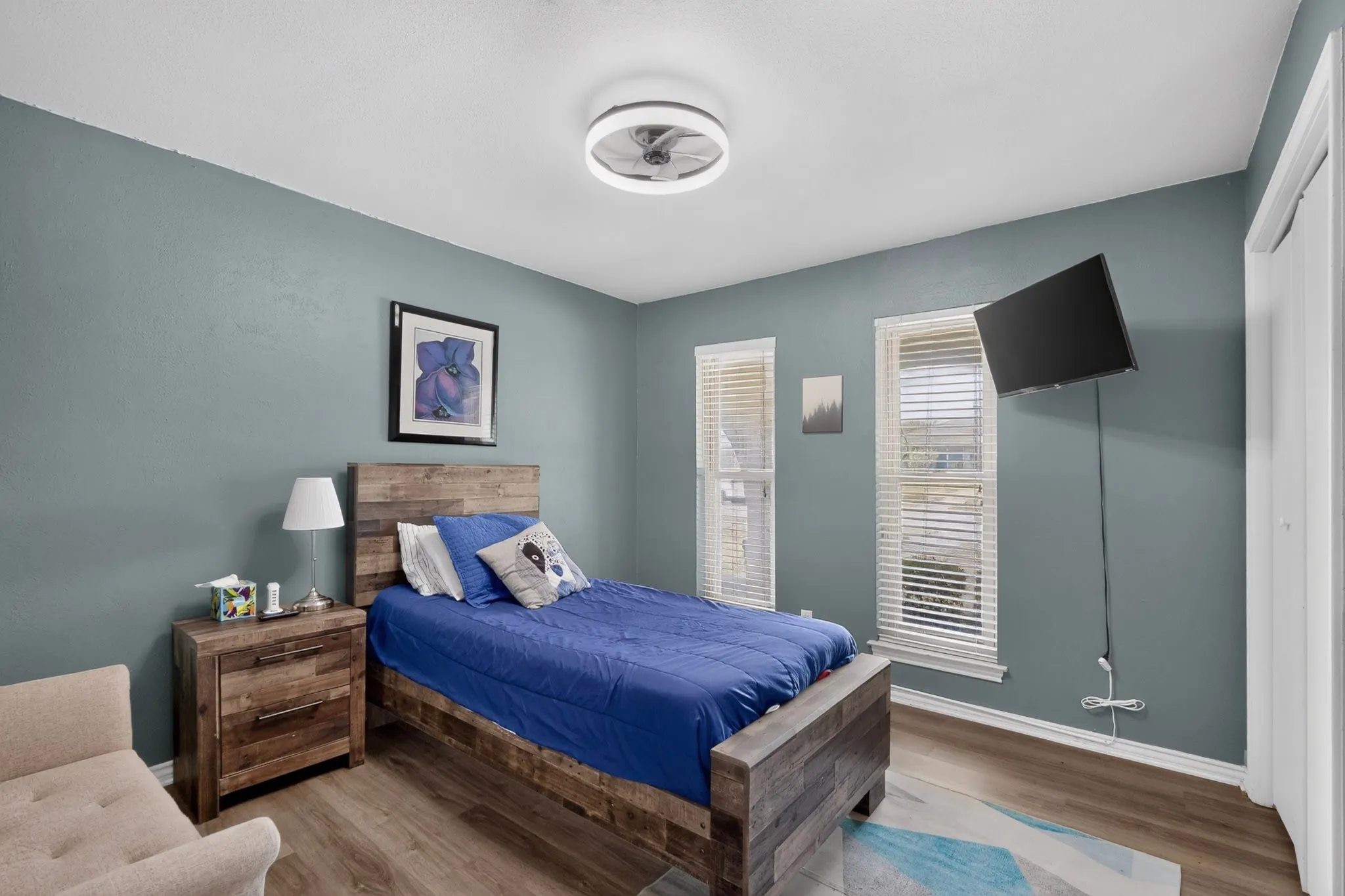 Wood-finish flooring throughout, two windows with blinds, and a built-in ceiling light fixture with fan