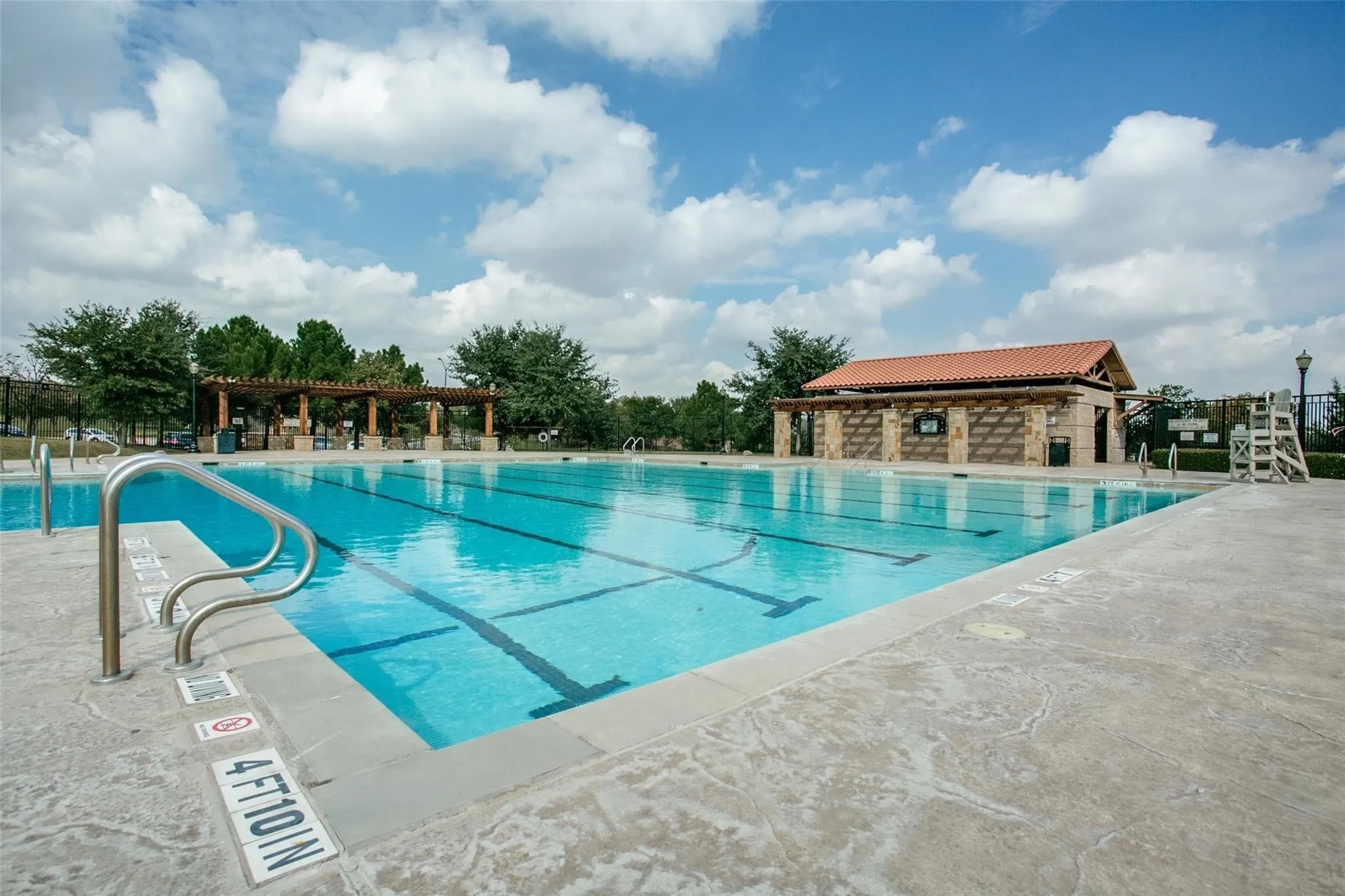 Expansive swimming pool featuring lane lines and stainless steel handrails