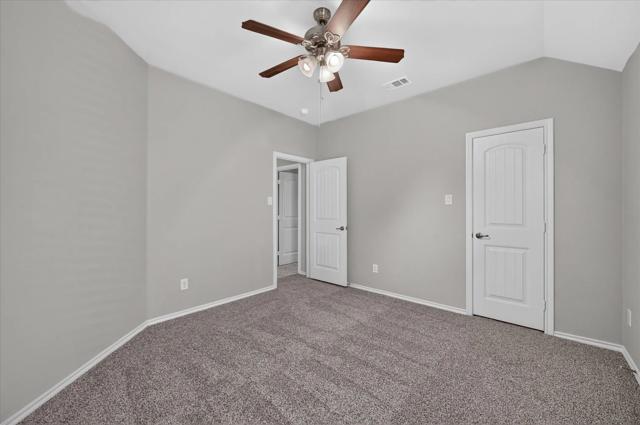 Vaulted ceiling with a ceiling fan, neutral wall paint, and gray carpeting