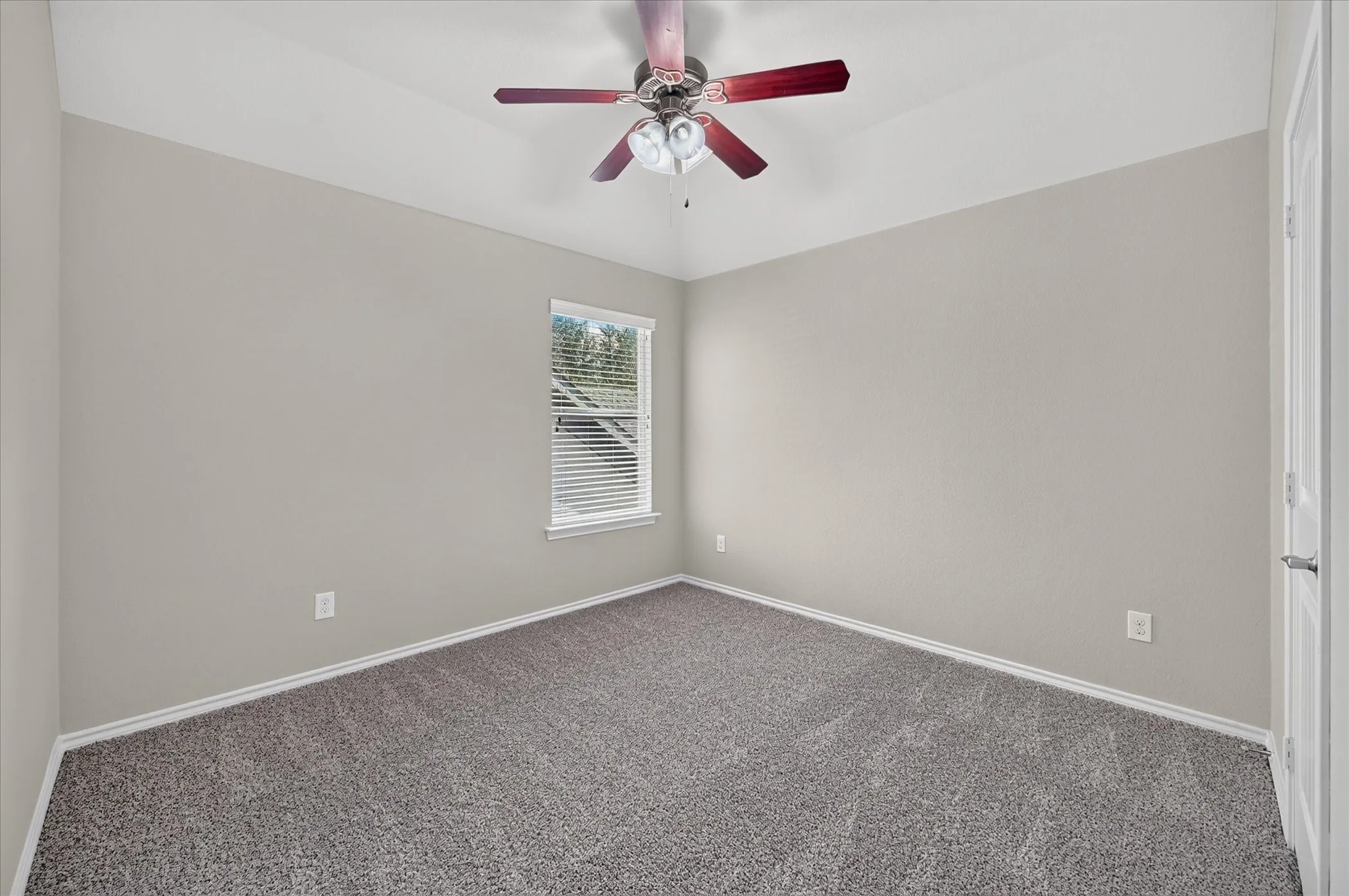 Vaulted ceiling, ceiling fan with light fixture, neutral wall finishes, carpeted flooring, and a single window with blinds