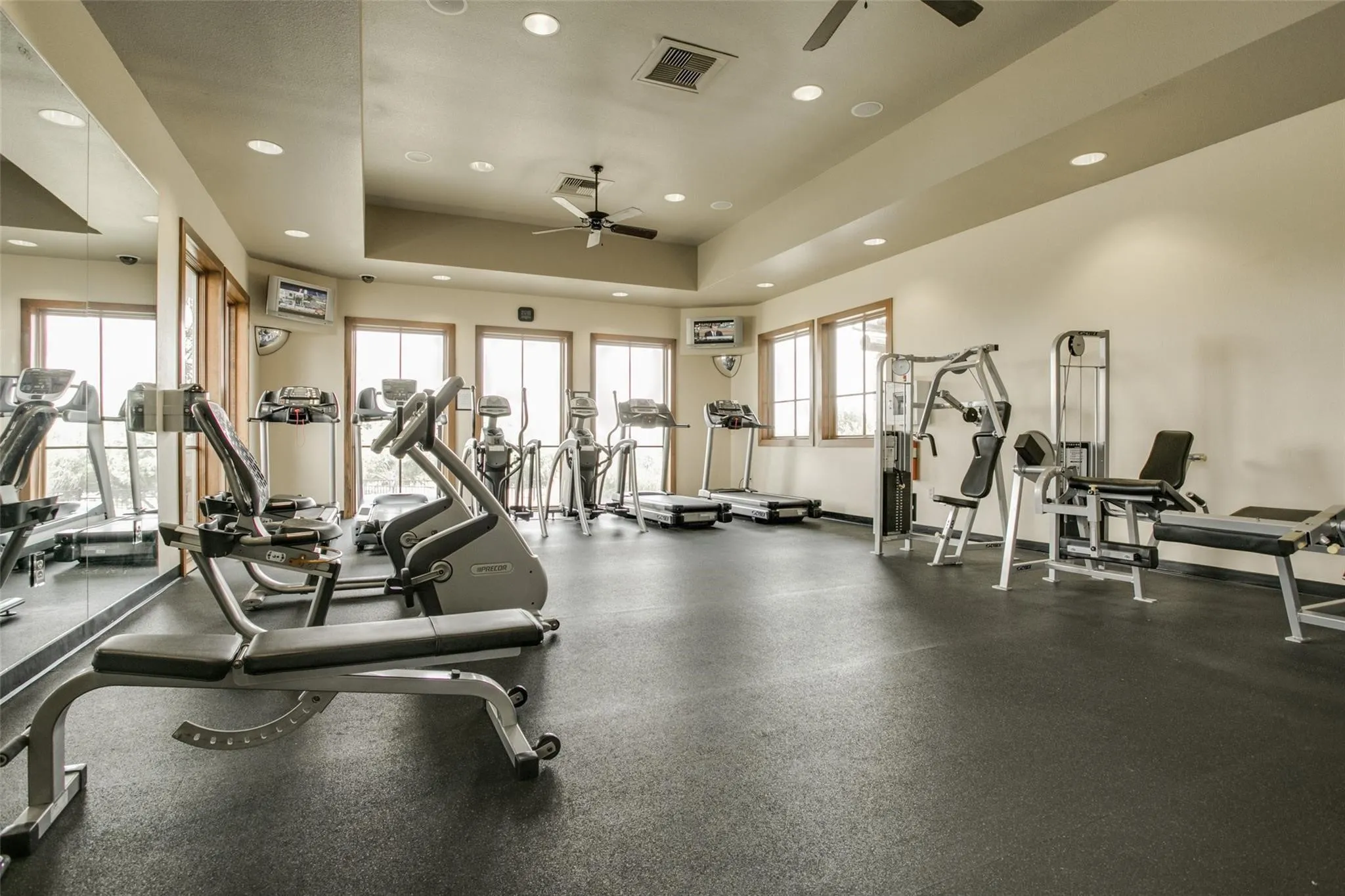 Fitness center featuring a rubberized floor, multiple windows, recessed lighting, and ceiling fans