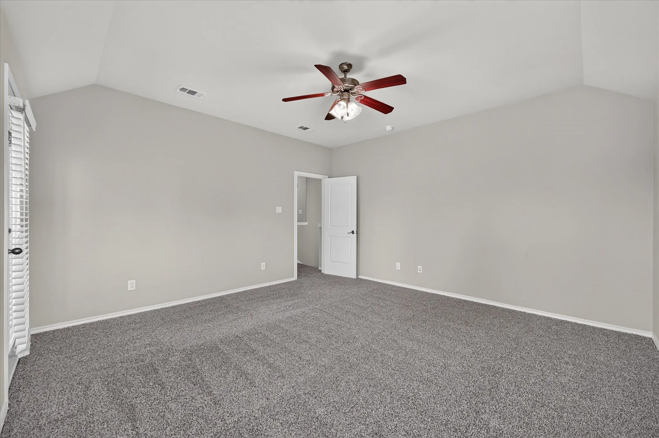 Vaulted ceiling, ceiling fan with light fixture, neutral wall paint, gray carpet flooring, and white trim