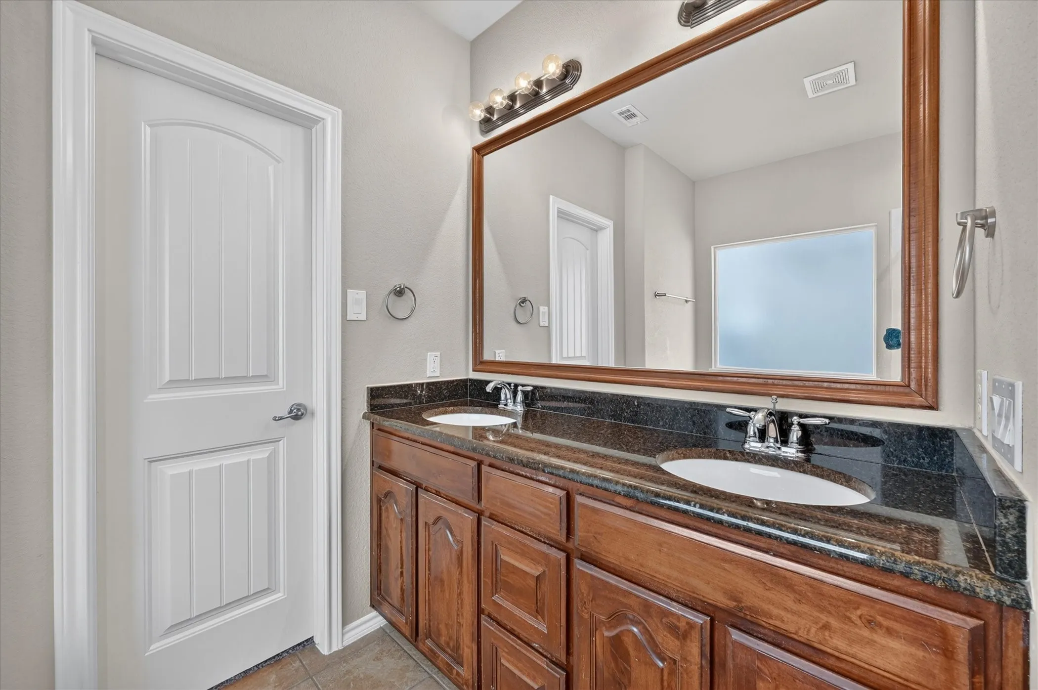Dual vanity with dark wood cabinetry and stone countertop