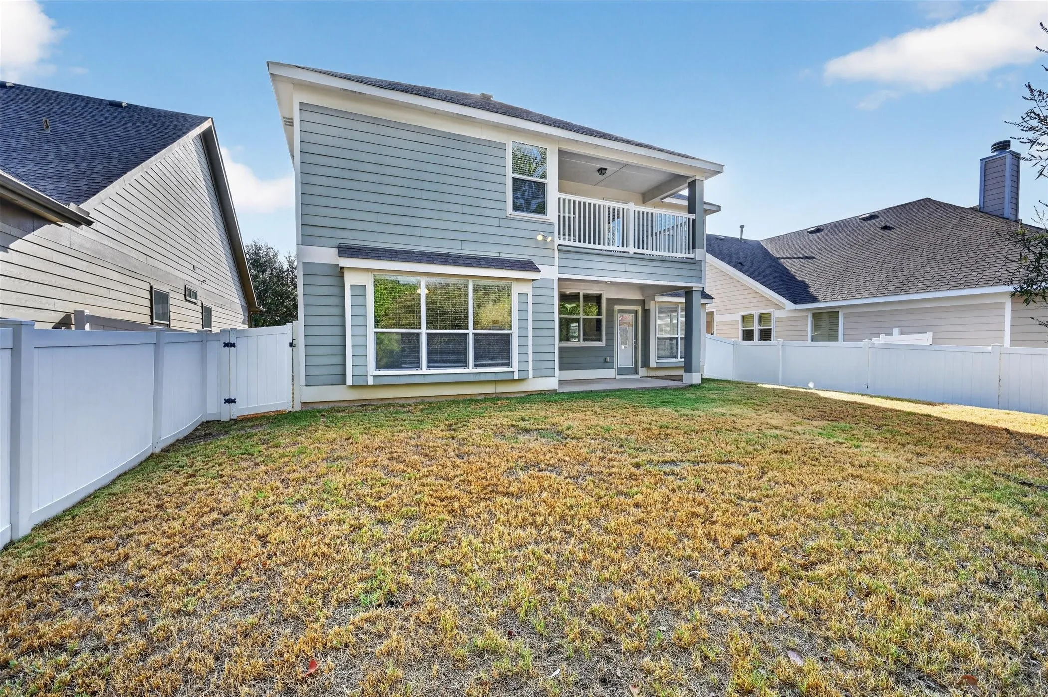 Two-story exterior with light blue siding, a covered balcony, and a ground-level covered patio