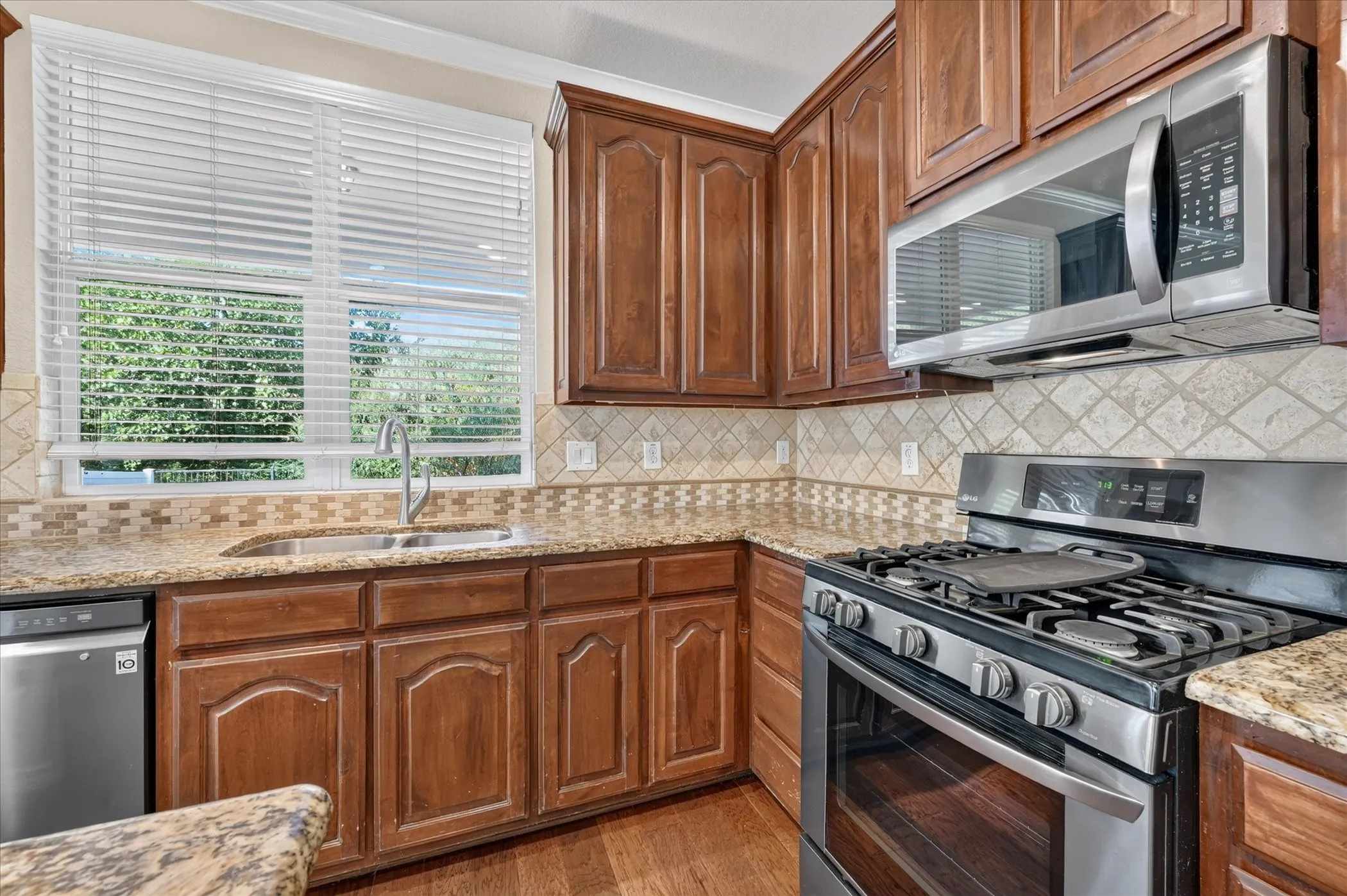 Kitchen featuring wood-finish cabinetry, stainless steel appliances, granite countertops, and a decorative tile backsplash