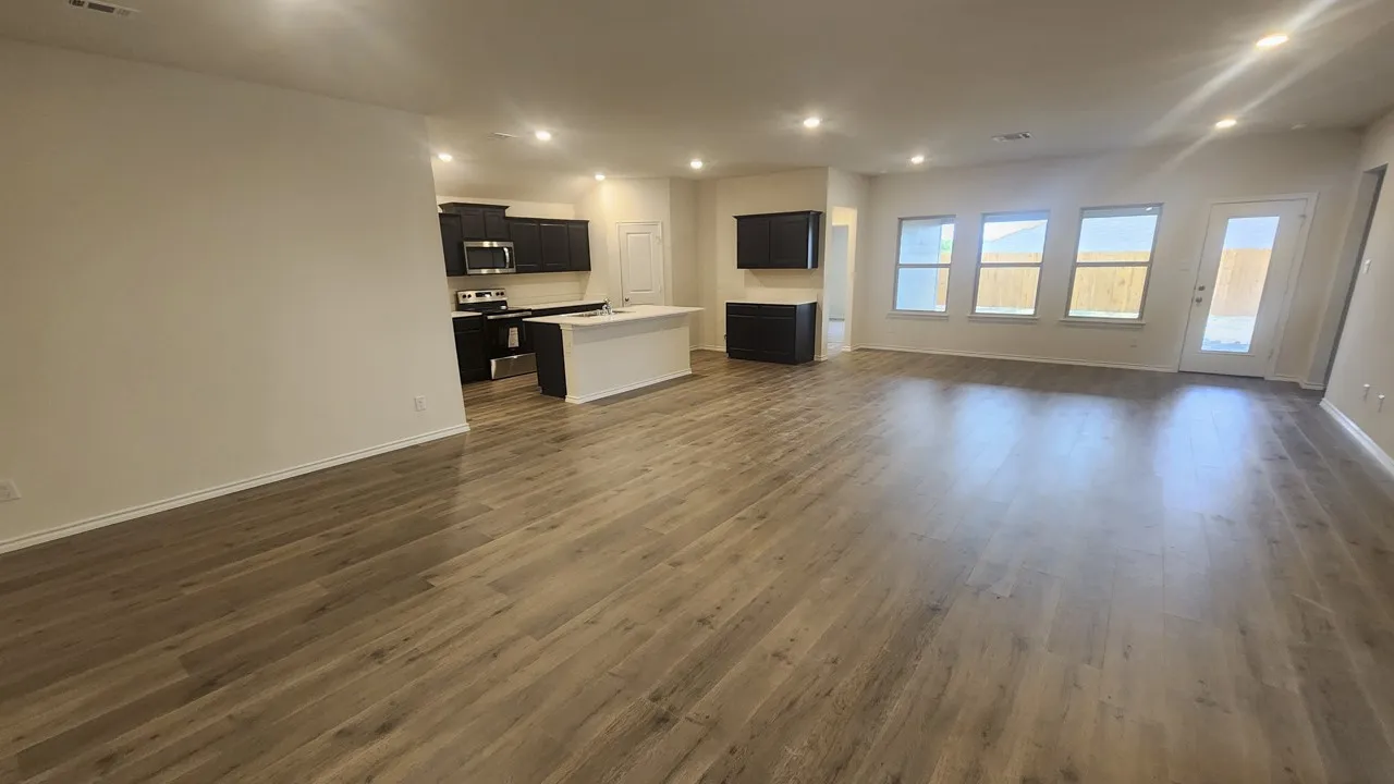 Open-concept living space featuring wood-finish flooring, recessed lighting, and multiple windows