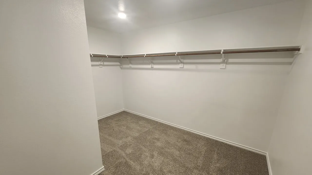 Recessed lighting, neutral wall paint, carpet flooring, and built-in closet shelving
