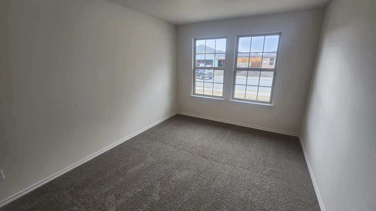 Light-filled room featuring neutral wall tones, gray carpeting, and two expansive windows