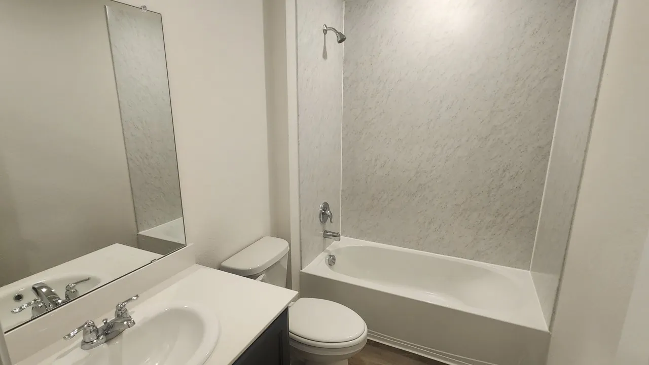 White vanity with integrated sink, chrome faucet, and rectangular mirror