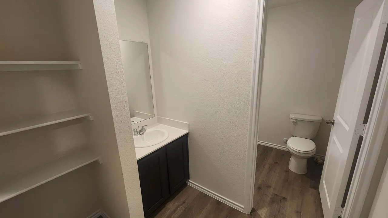 Vanity with integrated sink, rectangular mirror, dark wood-finish cabinetry, and wood-finish flooring
