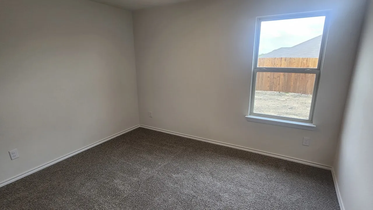 Neutral wall color, carpet flooring, and a single window with a white frame