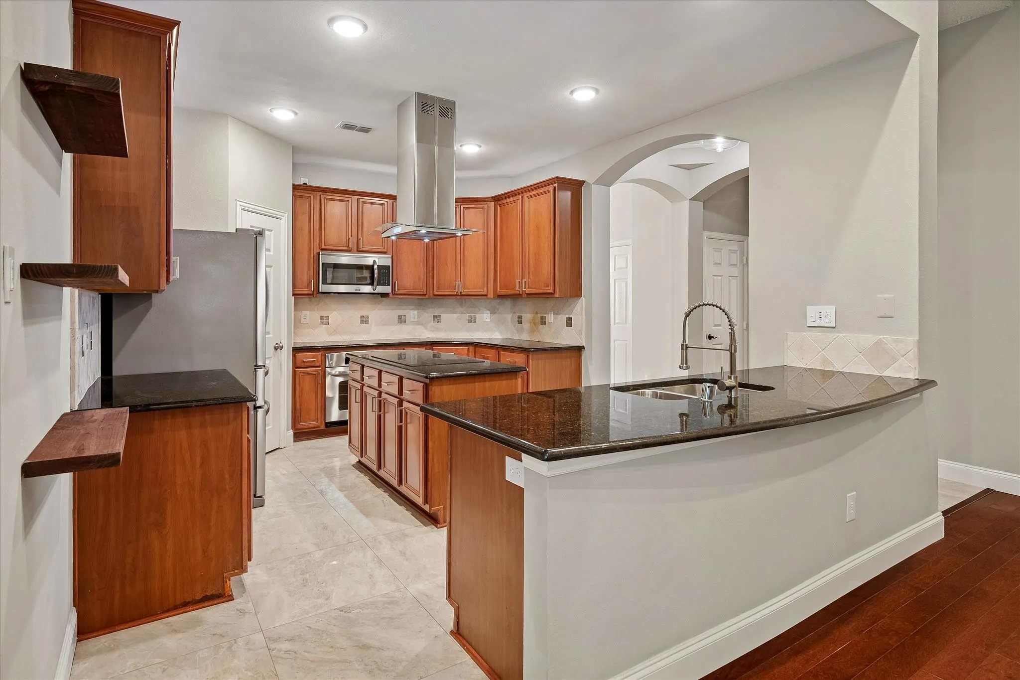 Kitchen featuring wood cabinetry, stainless steel appliances, dark countertops, a central island, and a tiled backsplash