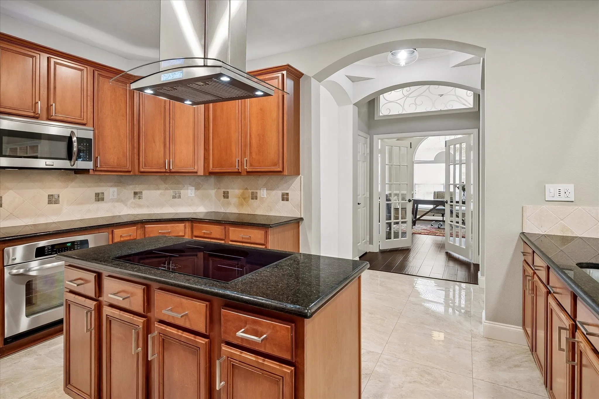 Kitchen featuring wood cabinetry, stainless steel appliances, a center island with a cooktop, and a matching backsplash