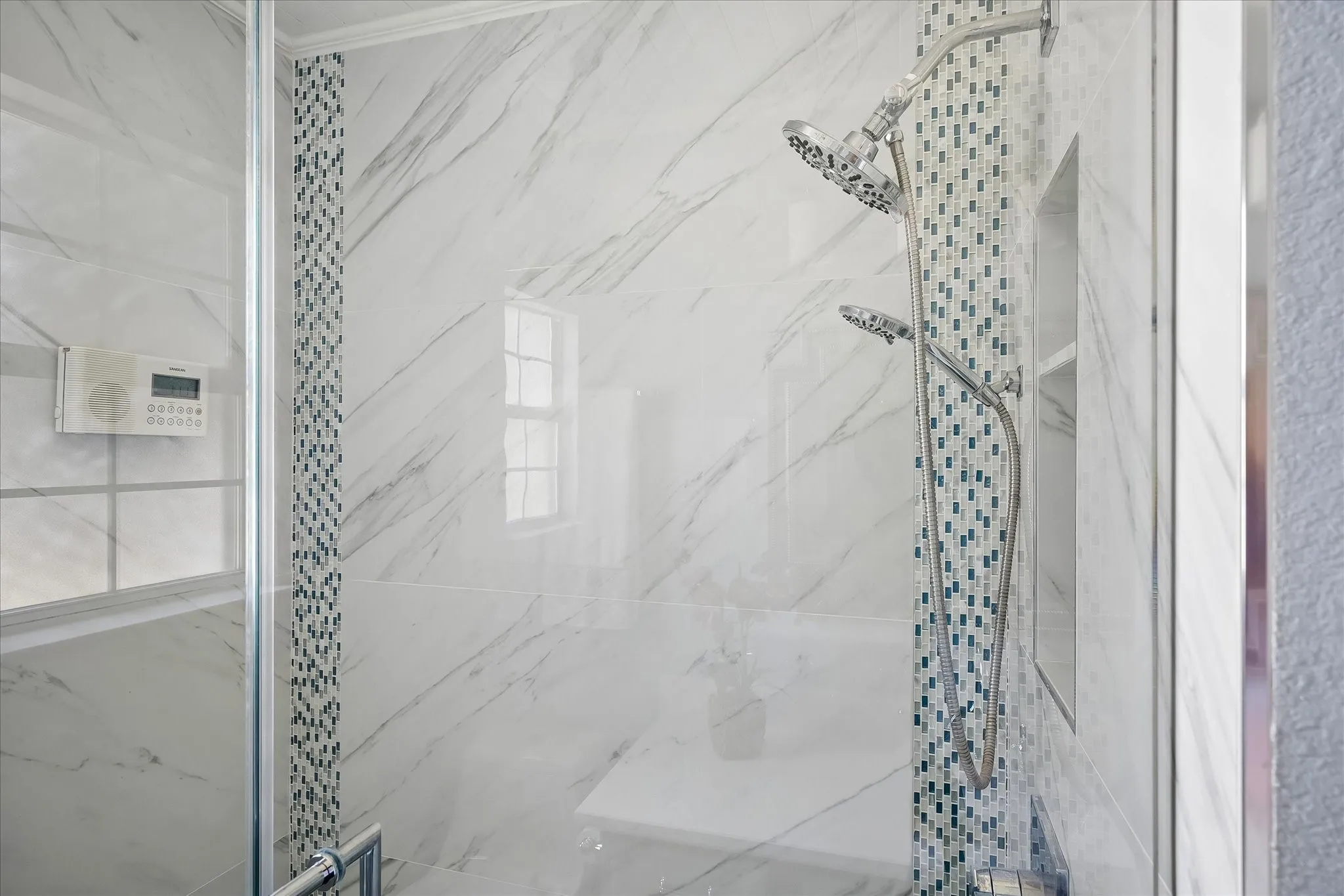 Glass-enclosed shower with marble-finish tile, mosaic tile accent, and dual shower heads