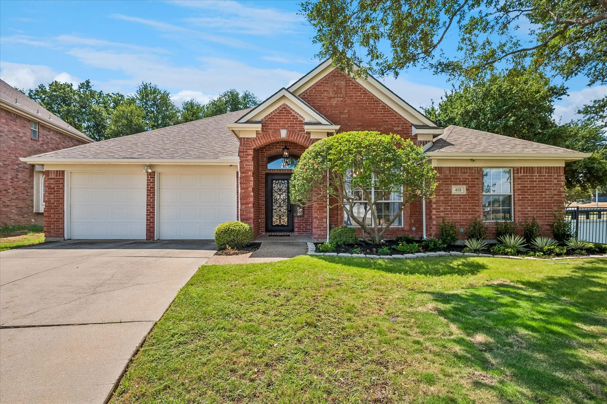 Brick facade with gabled roofline, arched entry, and a two-car garage