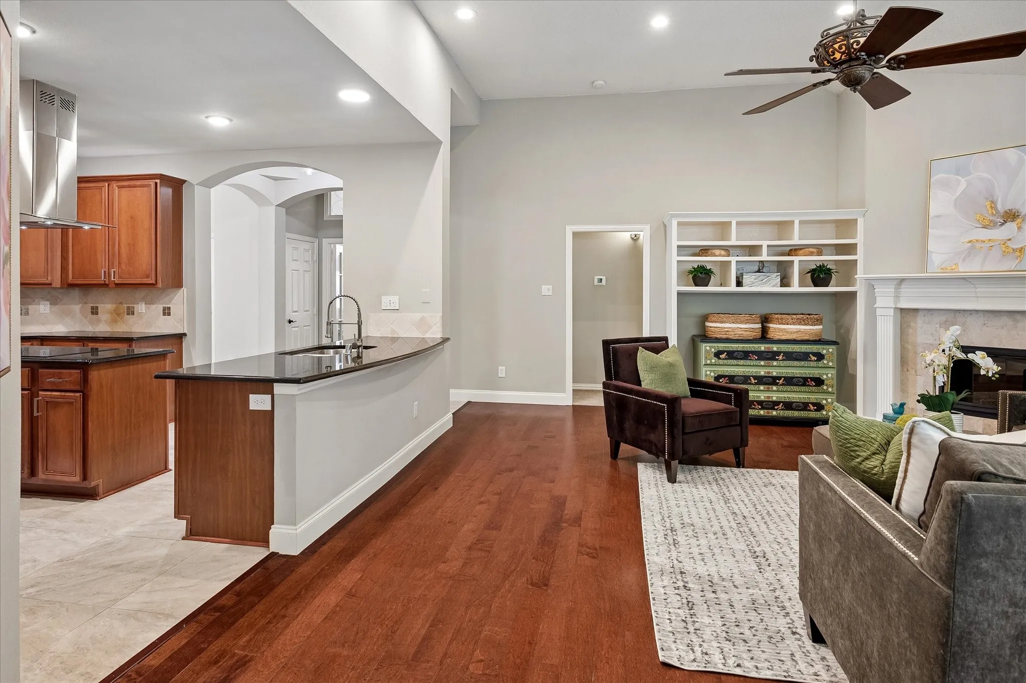 Hardwood flooring, recessed lighting, and a built-in shelving unit with an arched doorway