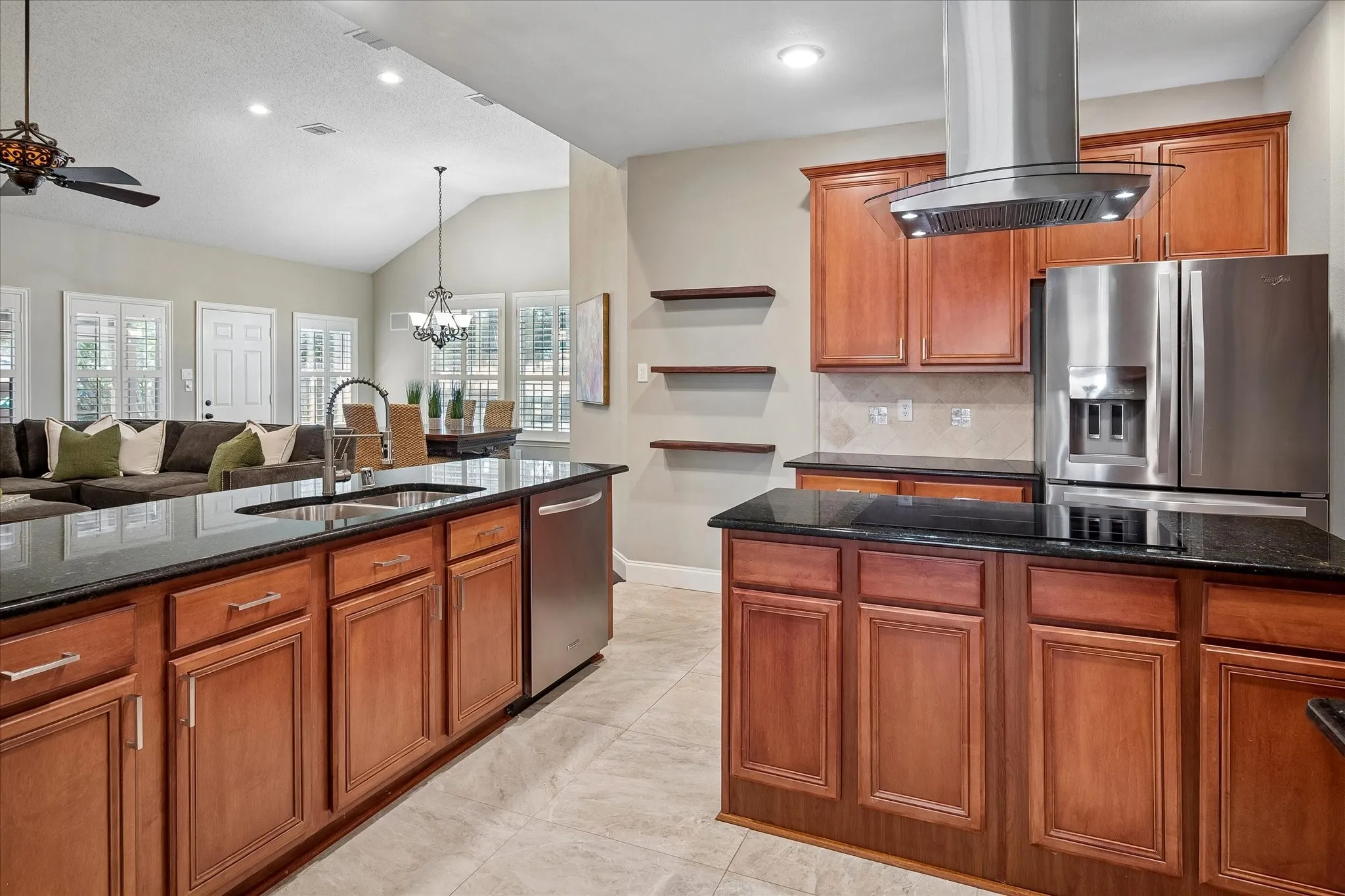 Kitchen featuring wood cabinetry, black countertops, stainless steel appliances, and tile flooring