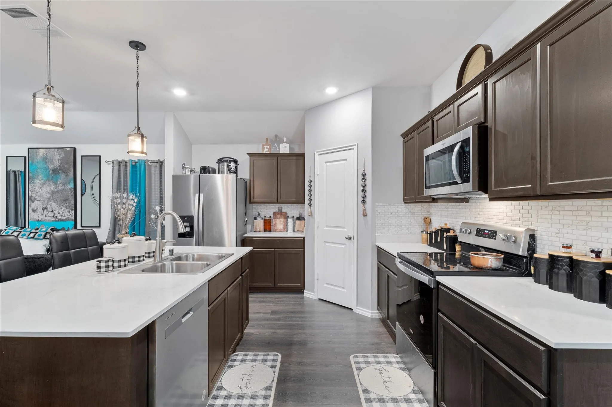 Kitchen featuring dark brown cabinetry, appliances with stainless steel finishes, tasteful backsplash, pendant lighting, and dark wood finished floors