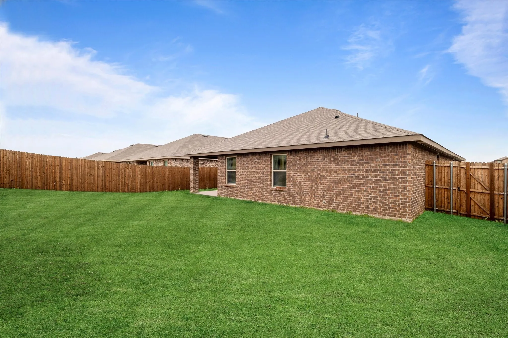 Rear view of property with a patio, a fenced backyard, brick siding, and a shingled roof