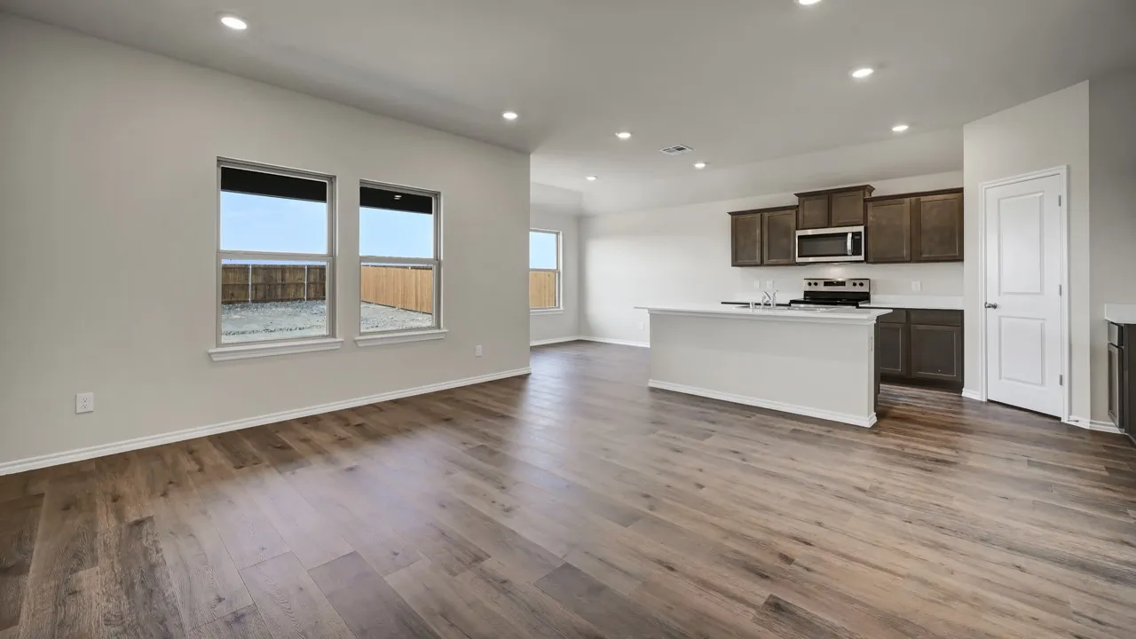 Open-concept living area featuring wood-finish flooring, recessed lighting, and multiple windows