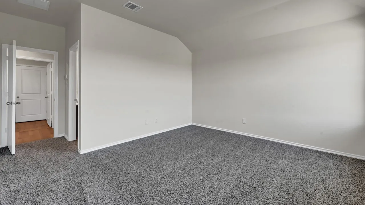 Spacious room featuring gray carpeting, white painted walls, and a vaulted ceiling