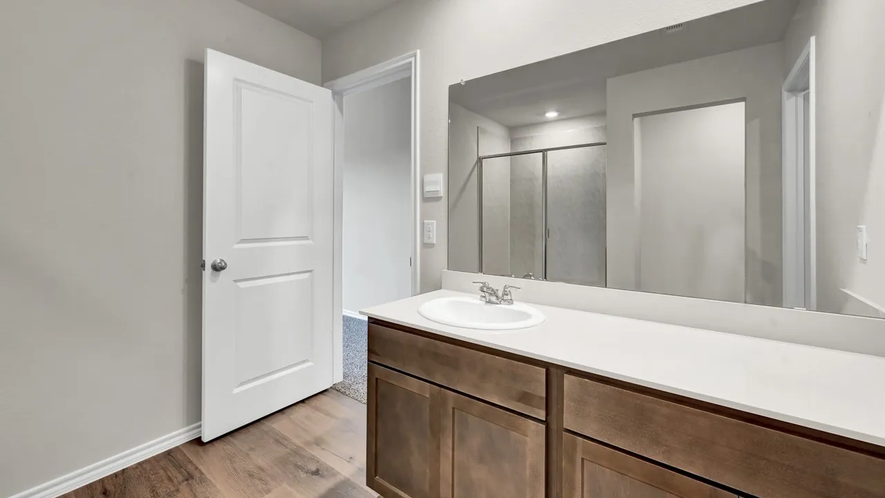 Wood-finish flooring, white vanity countertop, integrated sink, and full-width vanity mirror