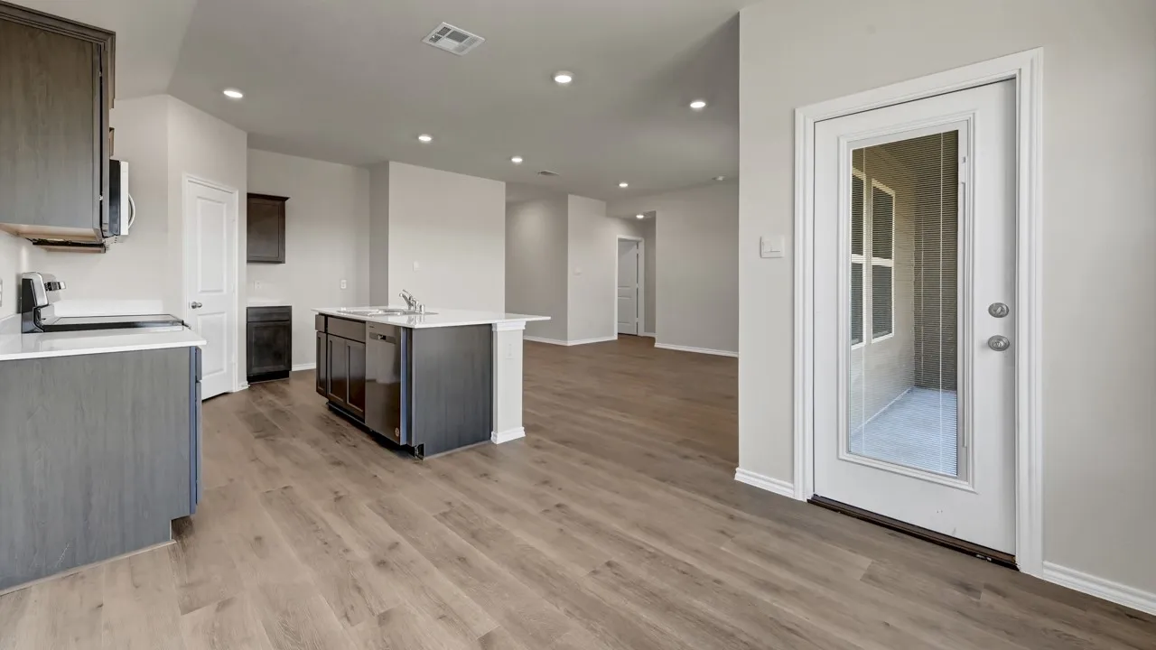 Kitchen featuring dark wood-finish cabinetry, light countertops, stainless steel appliances, and a central island with a sink