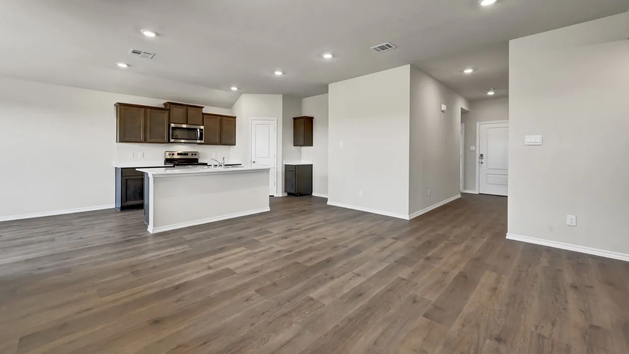Open-concept living area featuring wood-finish flooring, recessed lighting, and a kitchen island with a built-in sink