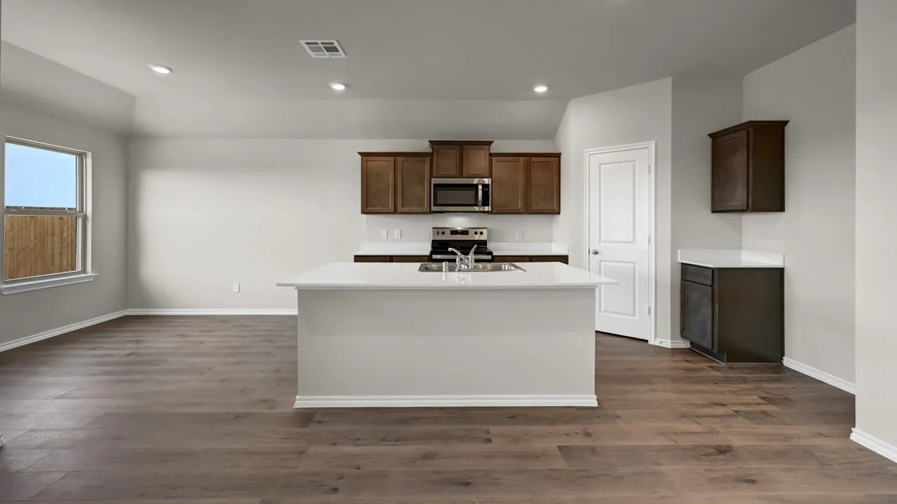 Open-concept kitchen and living area featuring wood-finish flooring, recessed lighting, a kitchen island with sink, and dark wood cabinetry