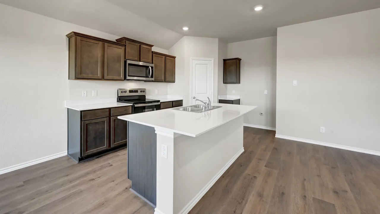 Kitchen featuring wood-finish flooring, dark wood cabinetry, white countertops, stainless steel appliances, and a central island with an undermount sink