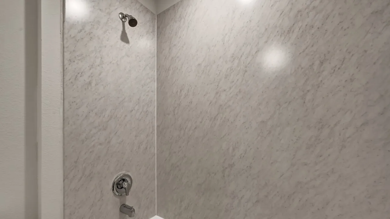 Shower surround with a textured light-toned finish, featuring a chrome shower head and dual-function faucet