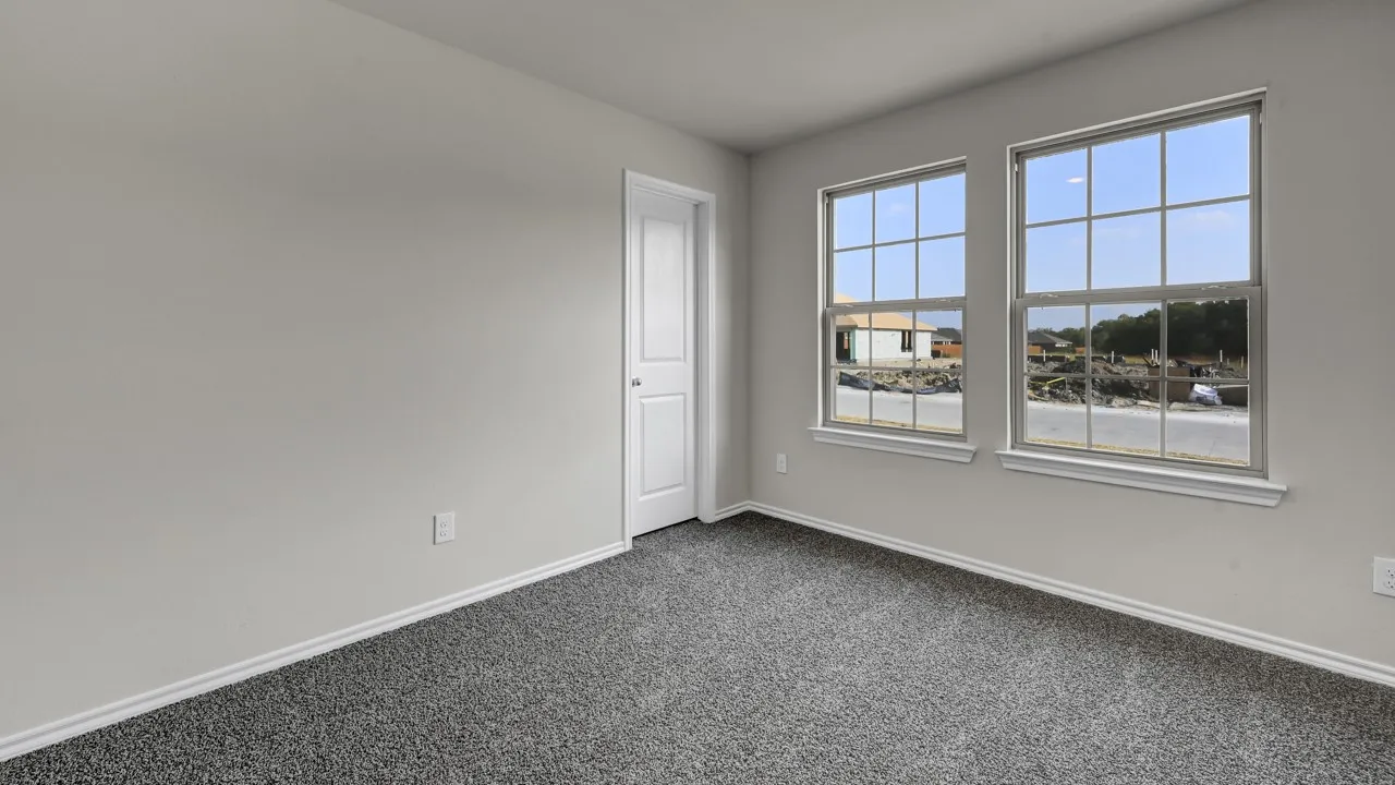 Light gray wall finish with white trim, two multi-pane windows with white sills, and gray carpeted flooring