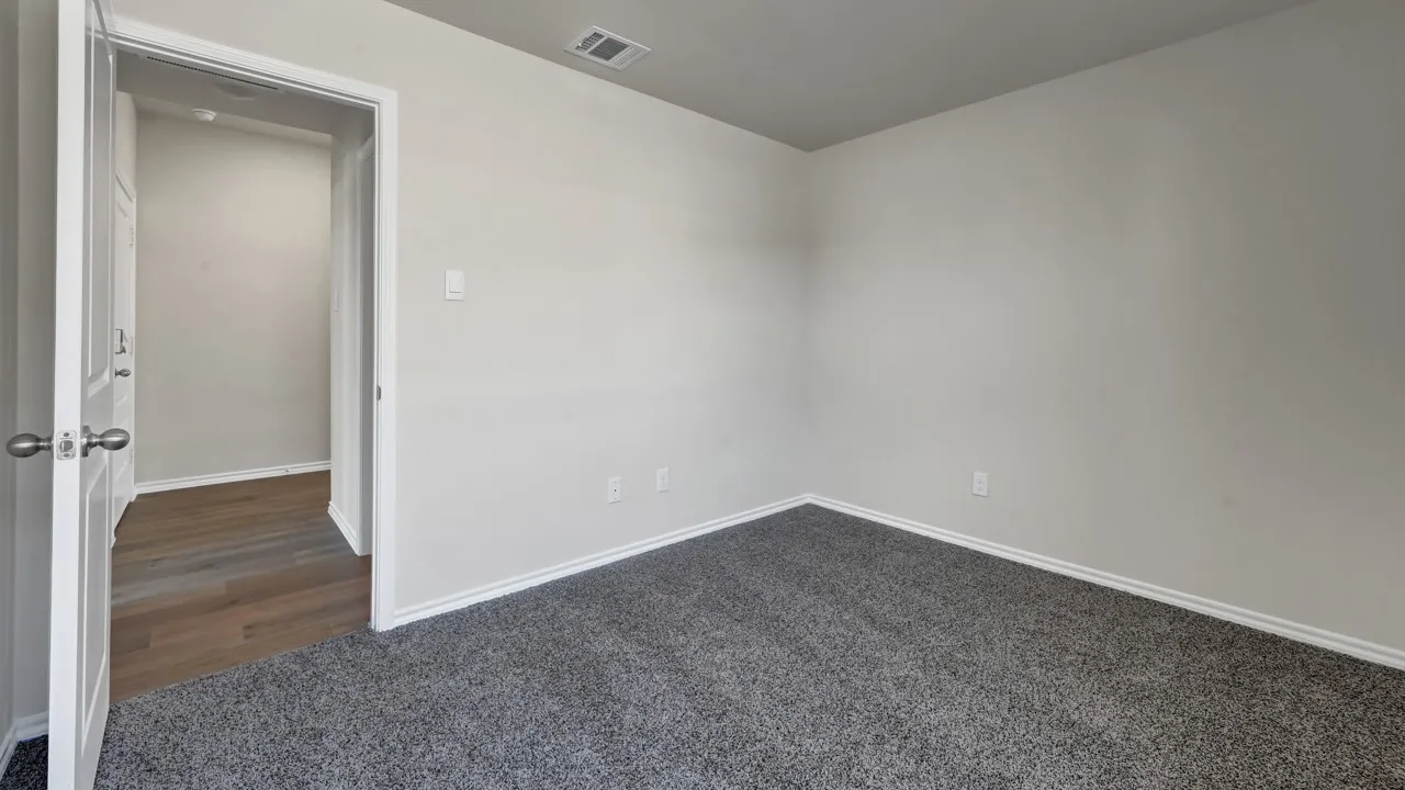 Light gray wall paint, gray carpet flooring, white trim, and a white interior door with a silver knob