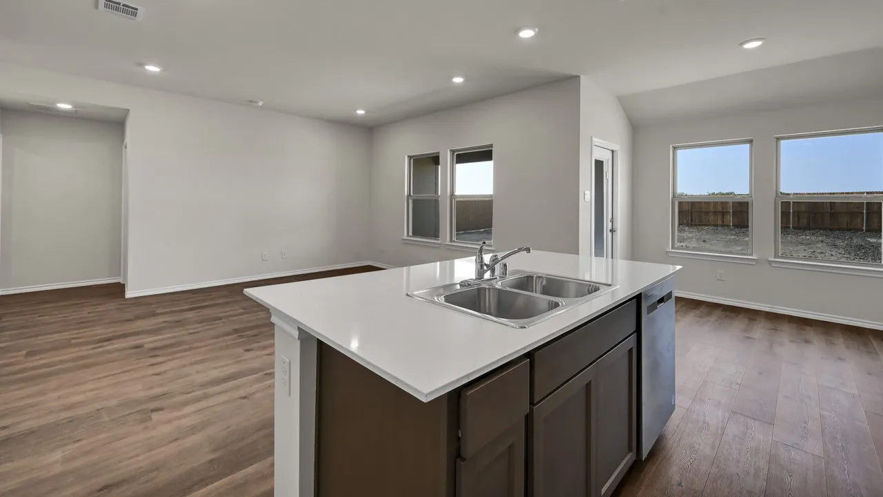Kitchen island with a dual basin sink, white countertops, and dark wood cabinetry