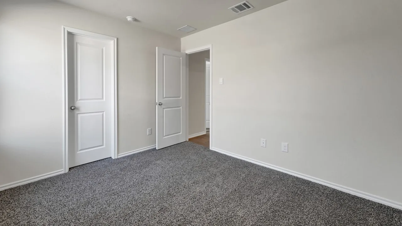 Neutral wall paint, two-panel interior doors, and grey carpet flooring