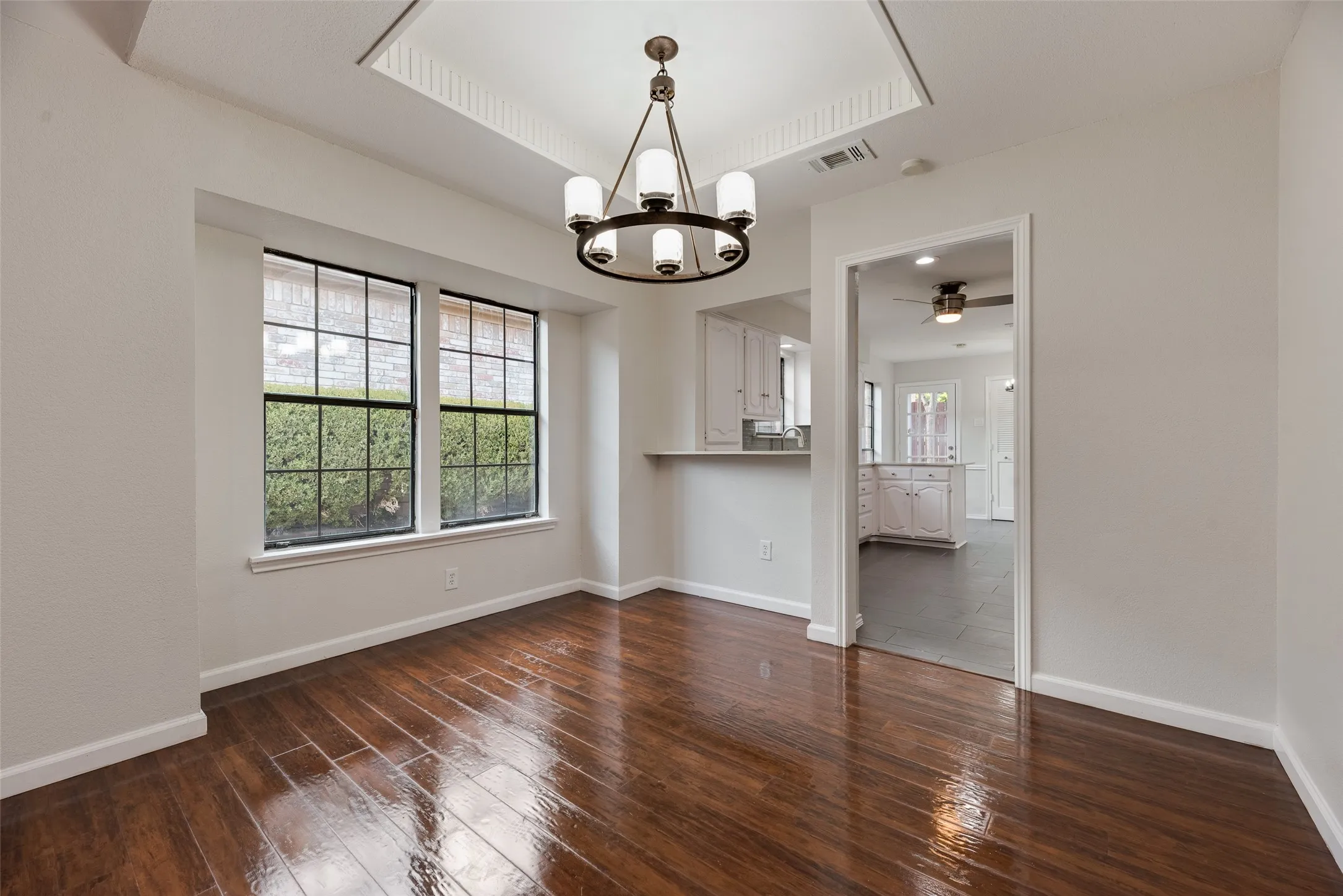 Hardwood flooring, recessed ceiling with crown molding, chandelier, and a breakfast bar