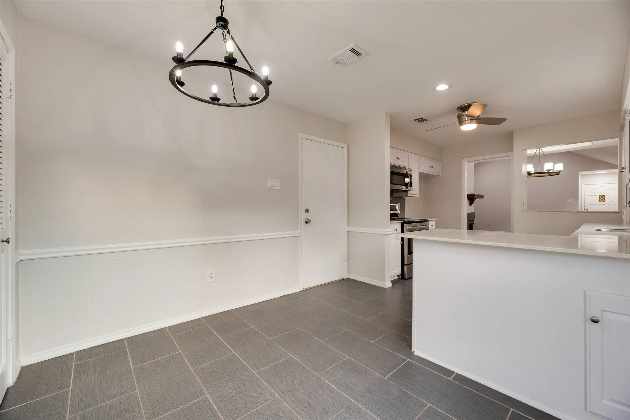 Porcelain tile flooring, crown molding, modern chandelier, breakfast bar with stone countertop, stainless steel appliances