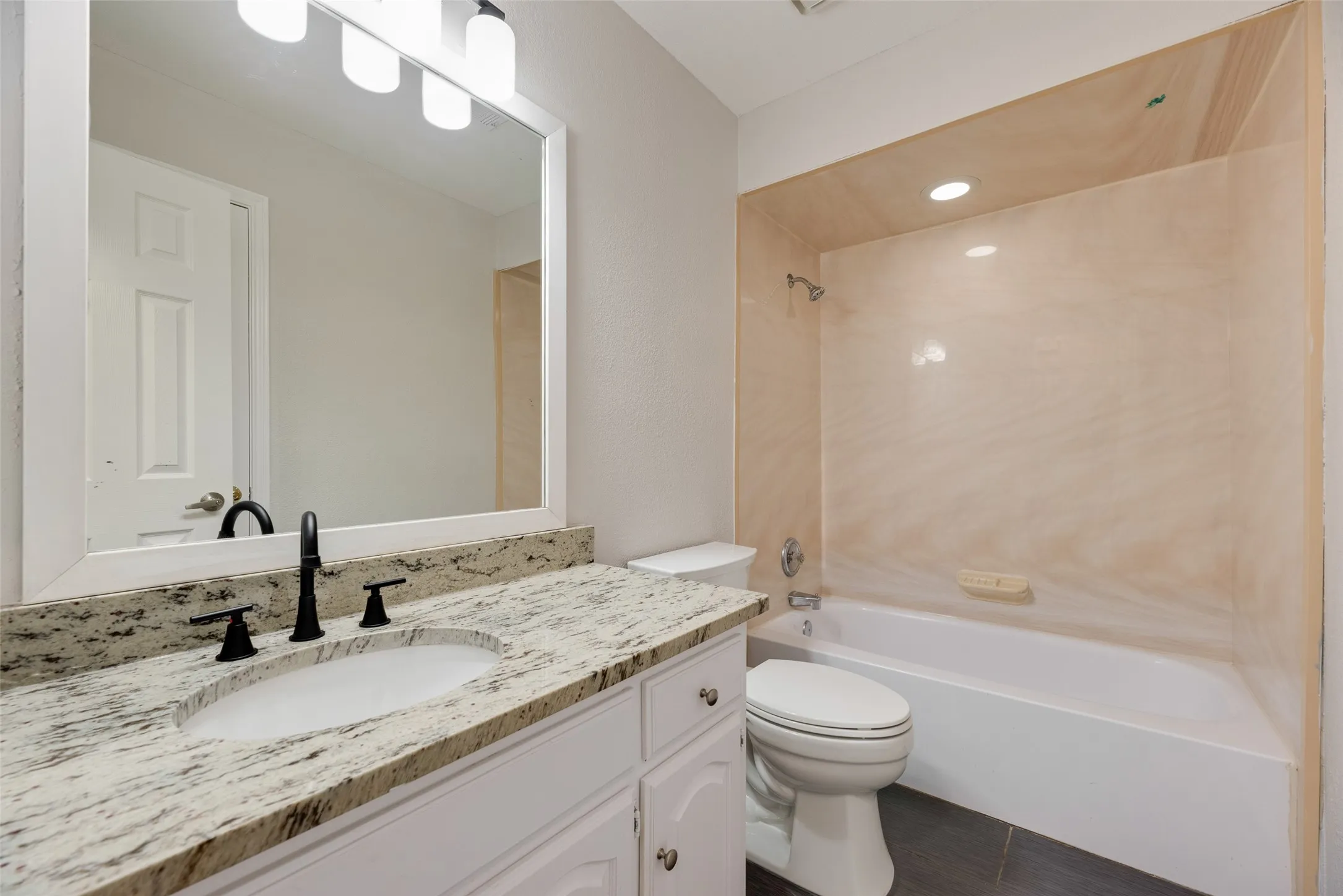 White vanity with an undermount sink, granite countertop, and matte black faucet