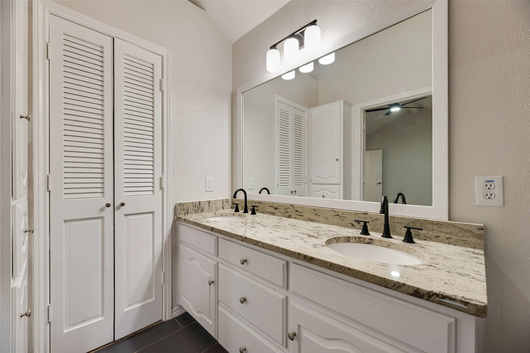Dual vanity with a stone countertop, undermount sinks, and matte black fixtures