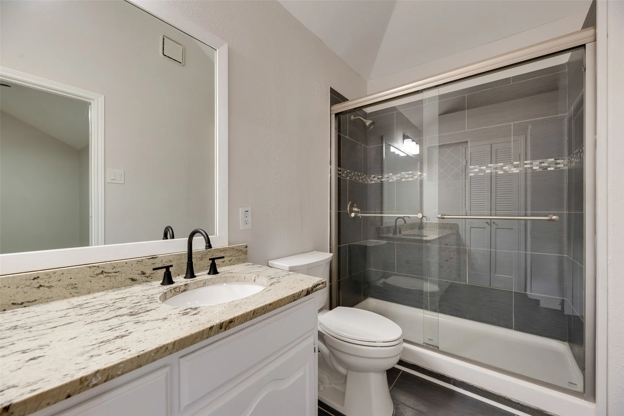 Vanity with a granite countertop, undermount sink, and matte black faucet