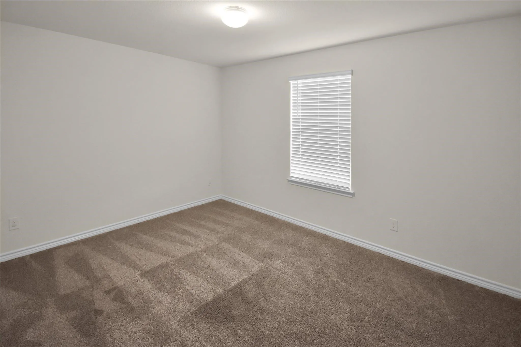 Neutral wall color, window with blinds, flush-mount ceiling light, and carpeted flooring