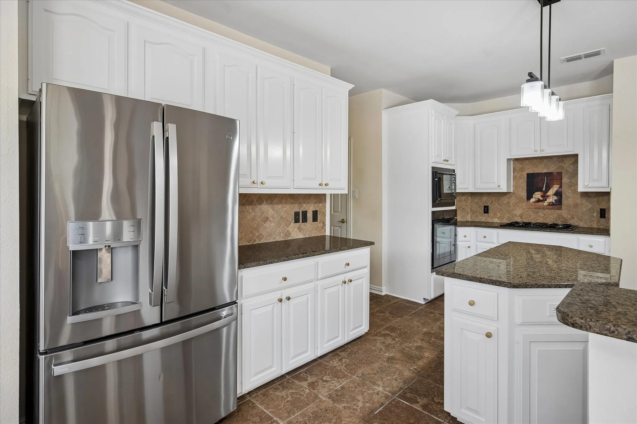 White cabinetry, stainless steel appliances, stone countertops, stone tile backsplash, and tile flooring