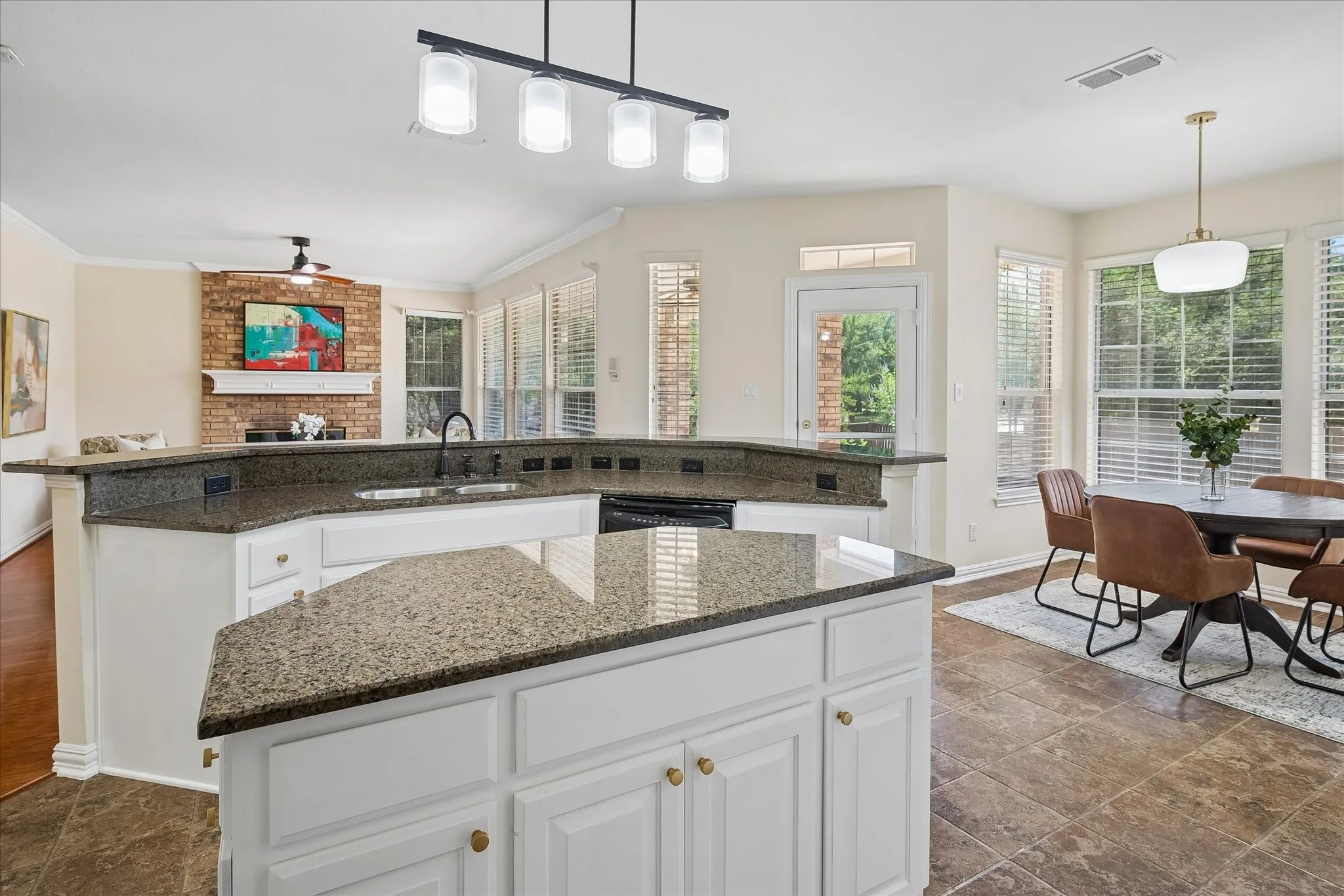 Kitchen featuring an expansive island with granite countertops, integrated sink, white cabinetry, and stainless steel appliances