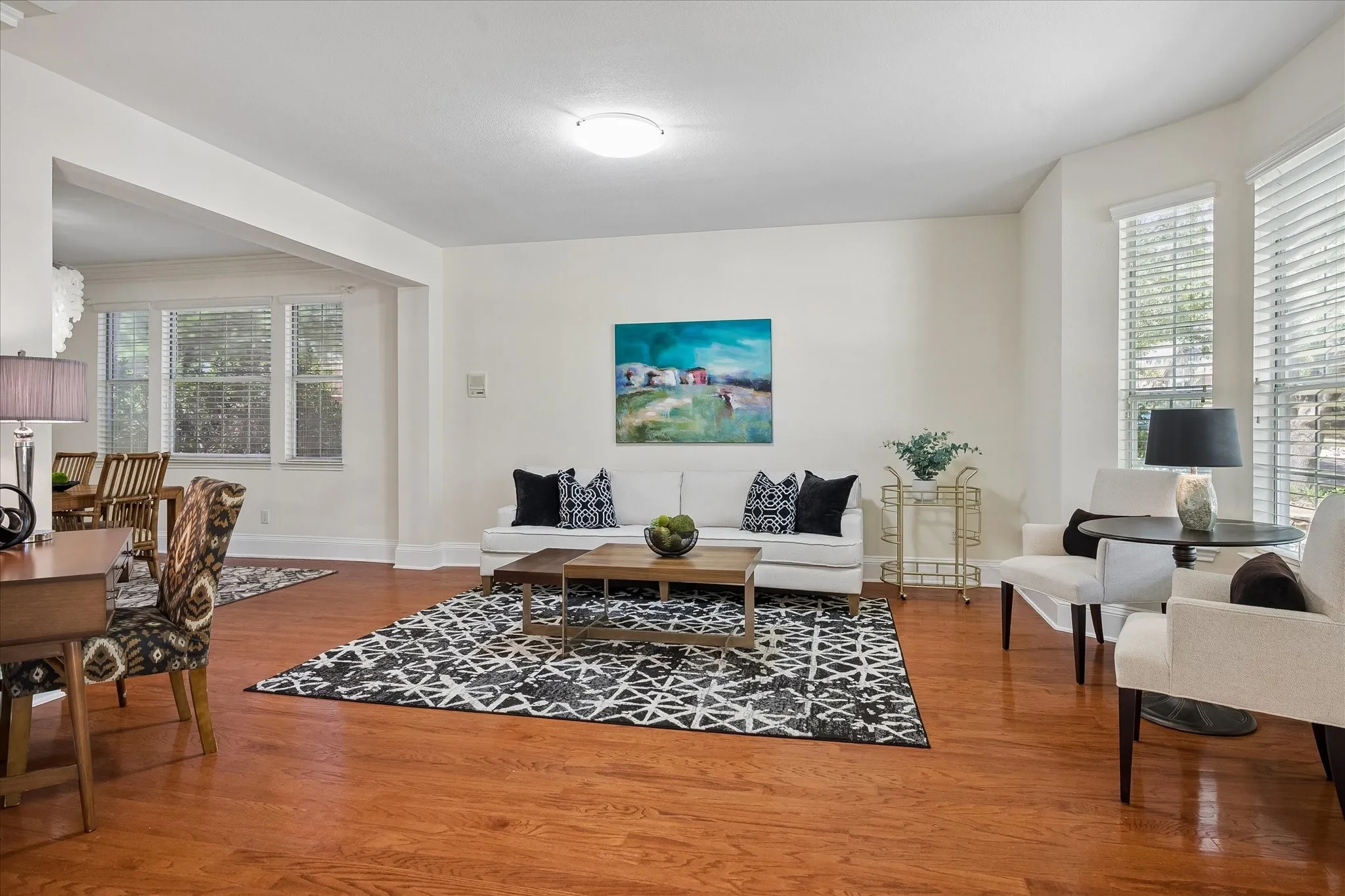 Hardwood flooring, cased openings, and multiple windows with blinds