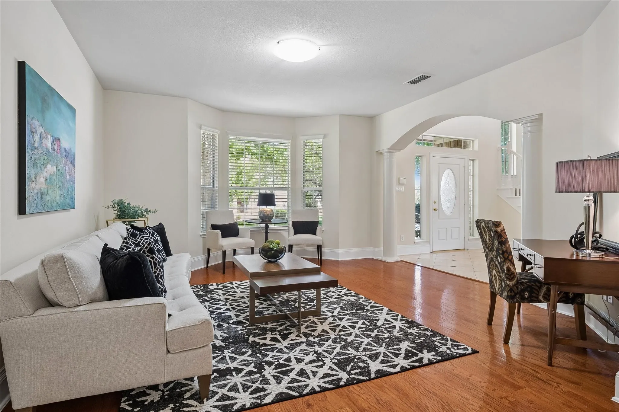 Hardwood-finish flooring, bay windows with blinds, arched entryway, and recessed lighting